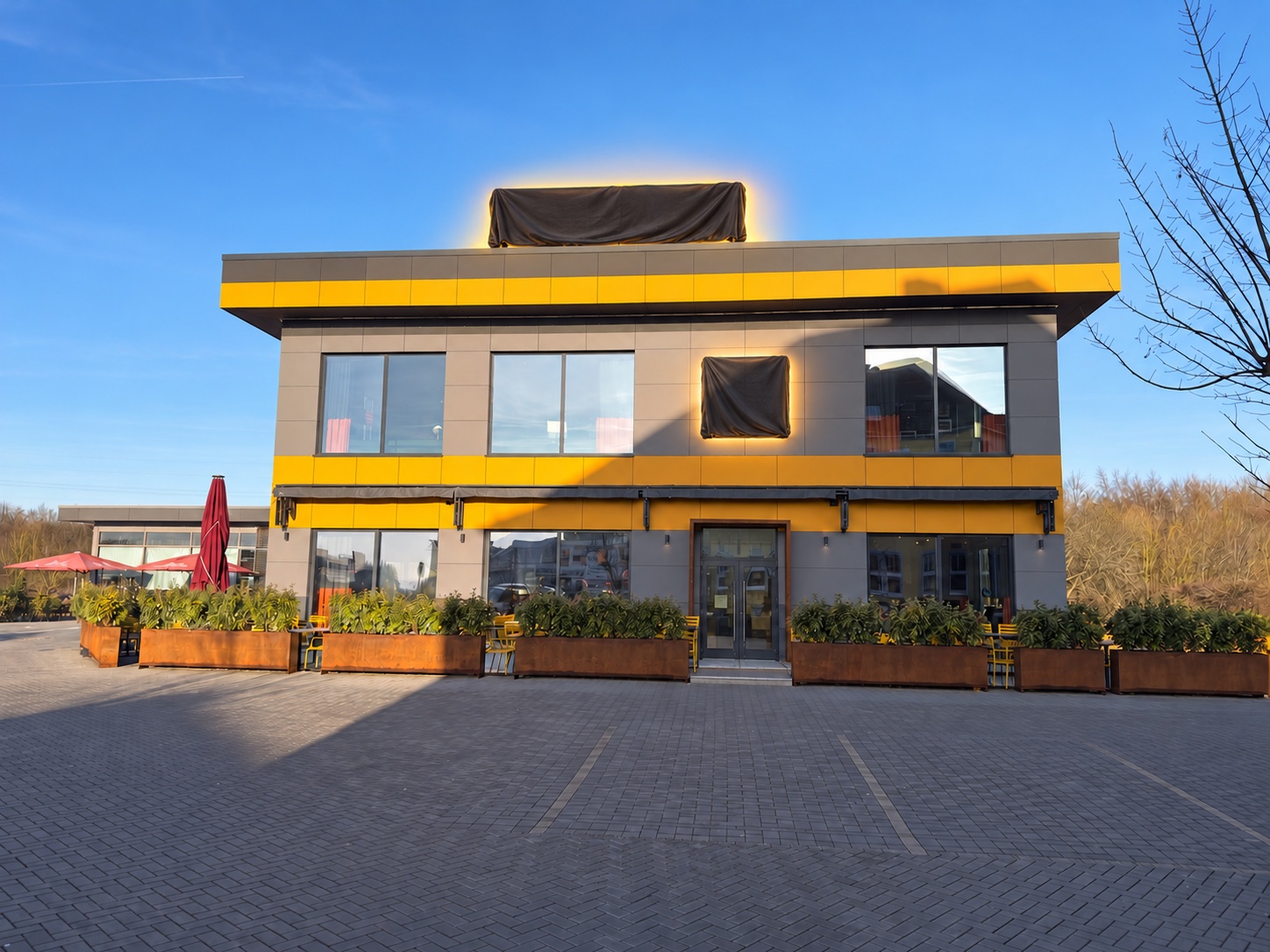 Die bereinigte Restaurantfassade mit verhüllten Schildern, hinter denen warmes Licht leuchtet.
